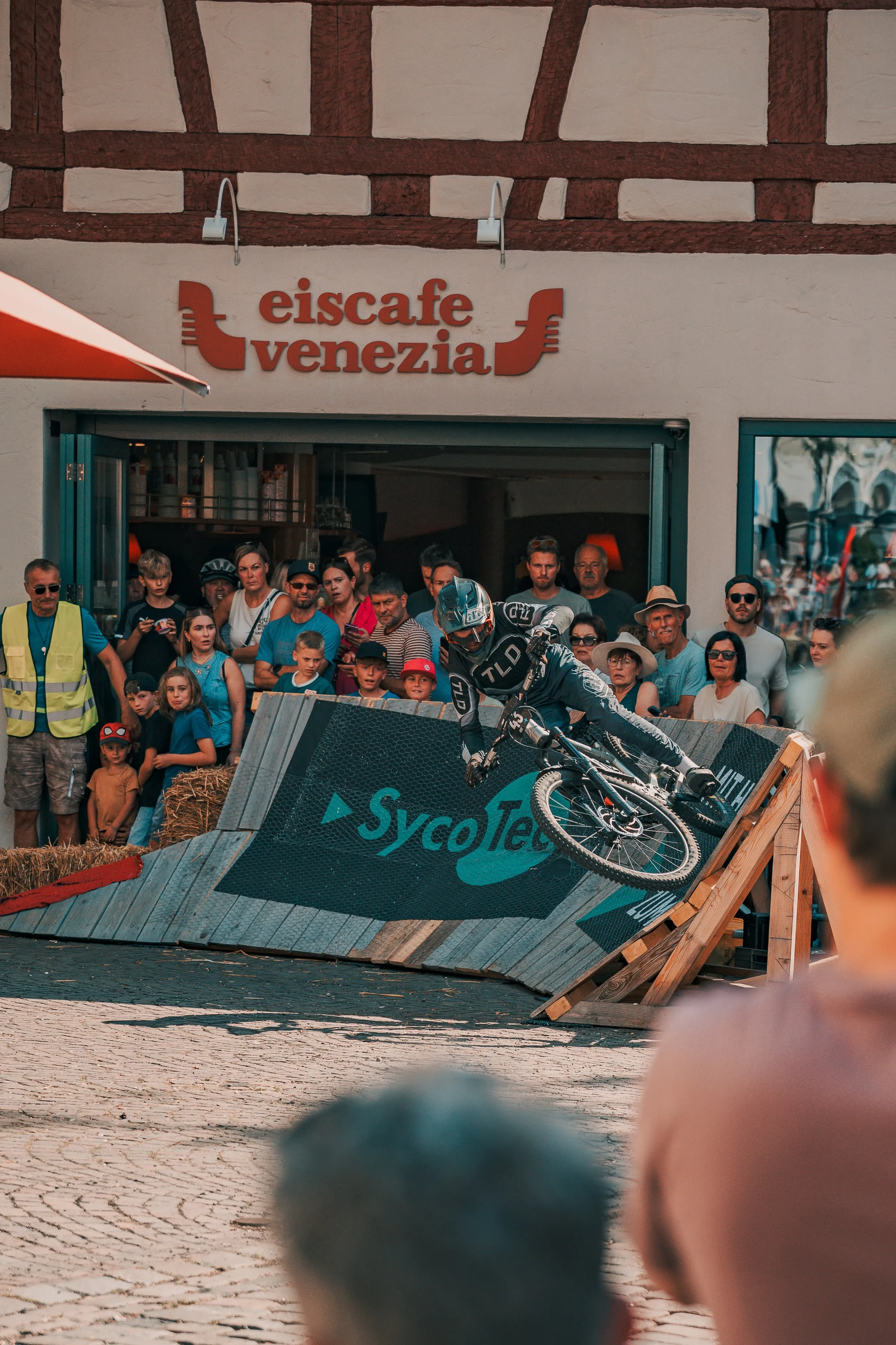 Mountainbike-Fahrer beim Urban Downhill Race Leutkirch 2026 auf der Rampe vor dem Eiscafé Venezia, dicht umringt von Zuschauern in der Altstadt